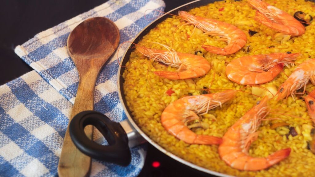 Paella au riz safrané garnie de crevettes et de poivrons dans sa poêle