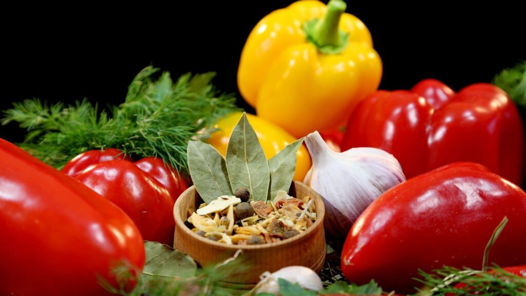 Poivrons rouges et jaunes, tomates et gousses d'ail réunis avant la préparation du sofrito