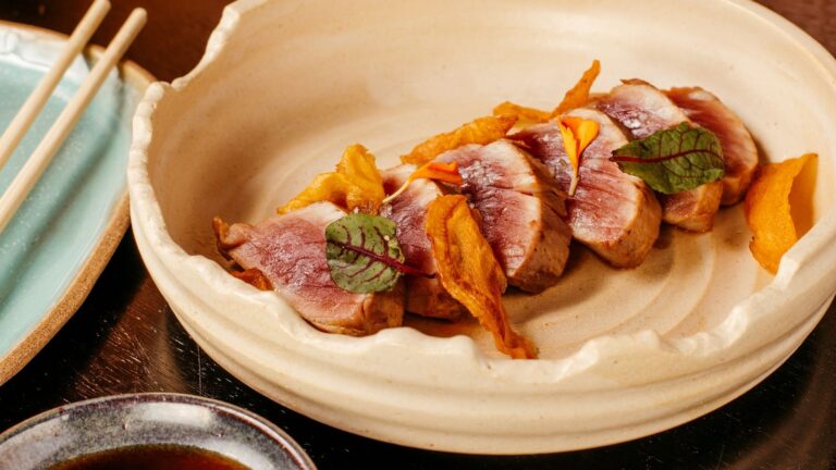 Tranches de magret de canard rosées dressées dans une assiette creuse