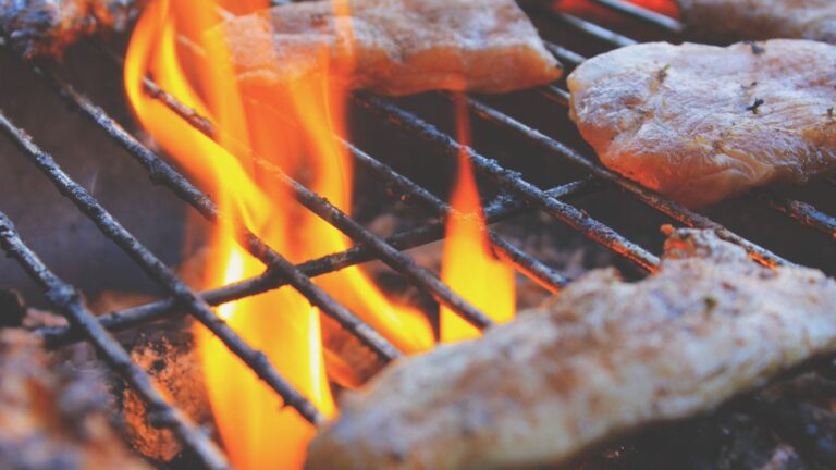 Brochettes de poulet mariné en train de griller au-dessus des flammes d'un barbecue