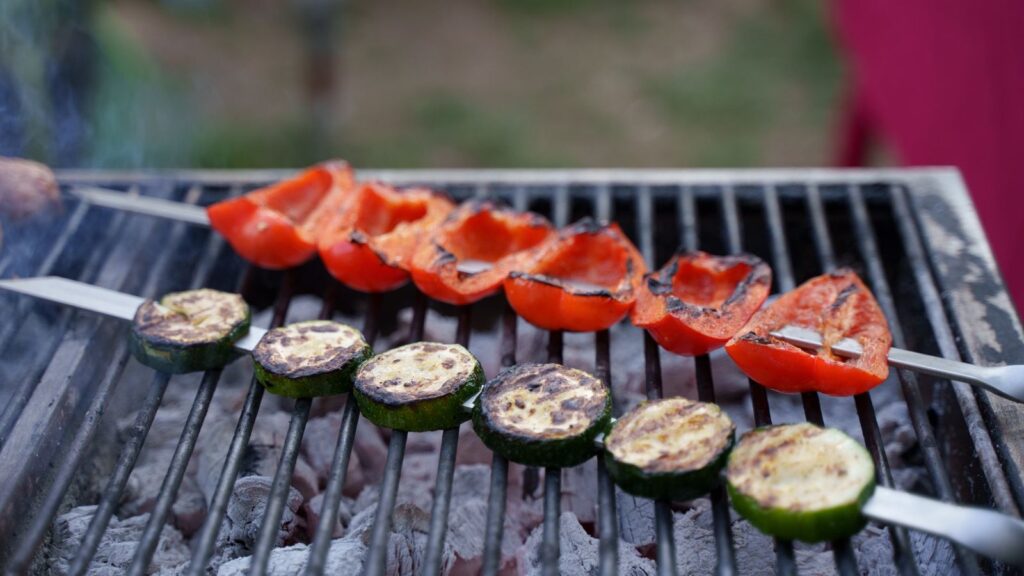 Poivrons et courgettes grillés posés sur la grille d'un barbecue