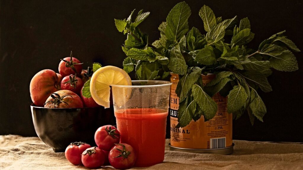 Tomates, menthe fraîche et jus de tomate réunis sur un plan de travail