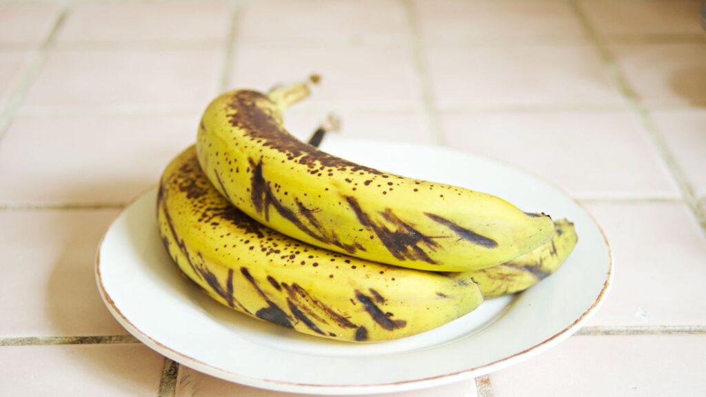 Bananes très mûres à la peau tachée de noir, posées sur une assiette blanche