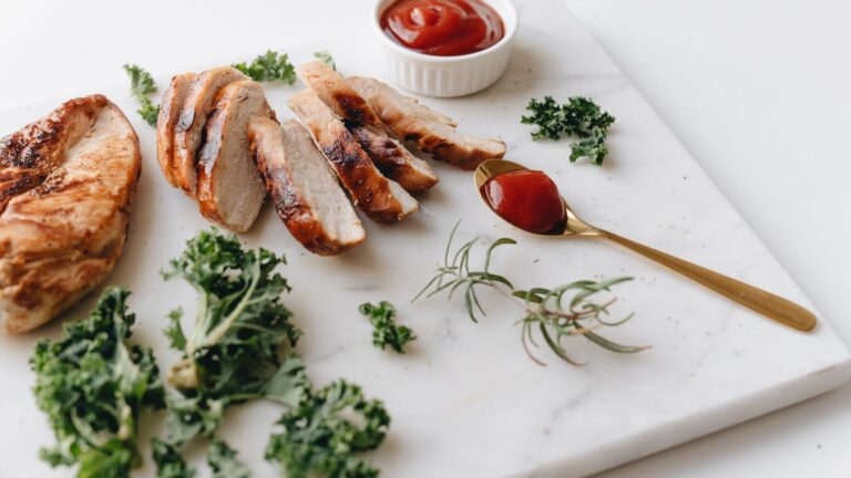 Blanc de poulet grillé tranché, dressé sur une planche avec des herbes fraîches