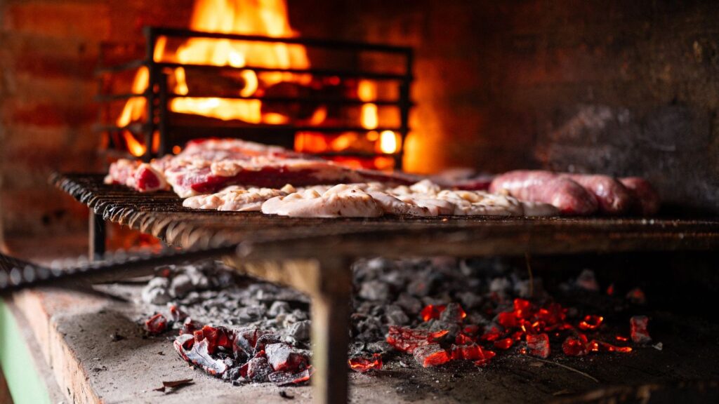 Viande en cuisson sur un barbecue, braises rougeoyantes en arrière-plan