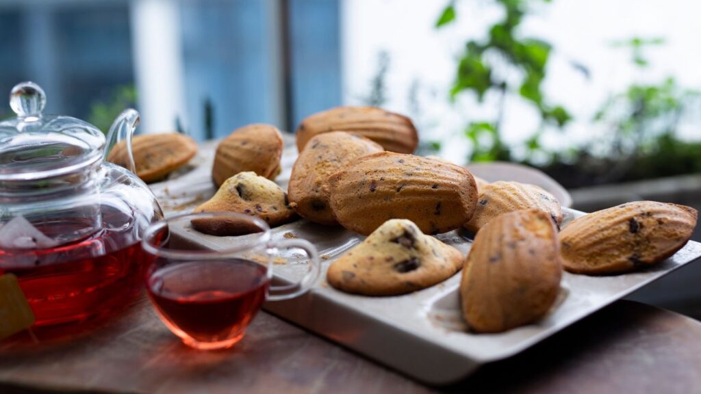 Madeleine tiède posée près d'une tasse, zeste de citron à côté