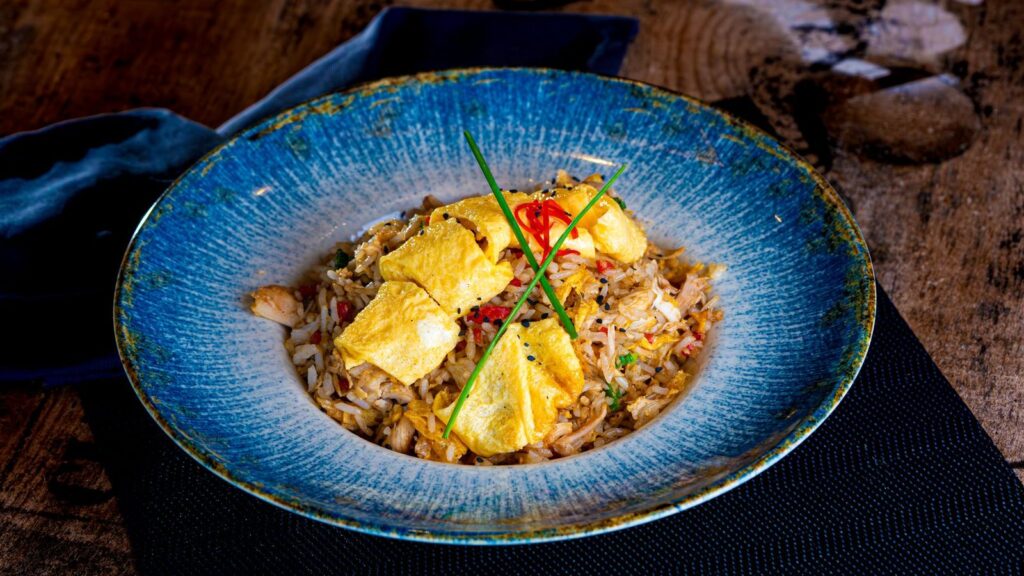 Bol de riz sauté aux œufs et aux herbes, servi dans une assiette creuse bleue